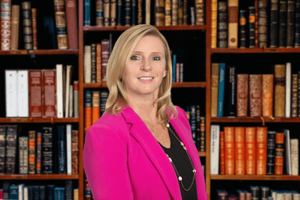 A picture of Kellie O'Shea standing in front of a bookshelf.